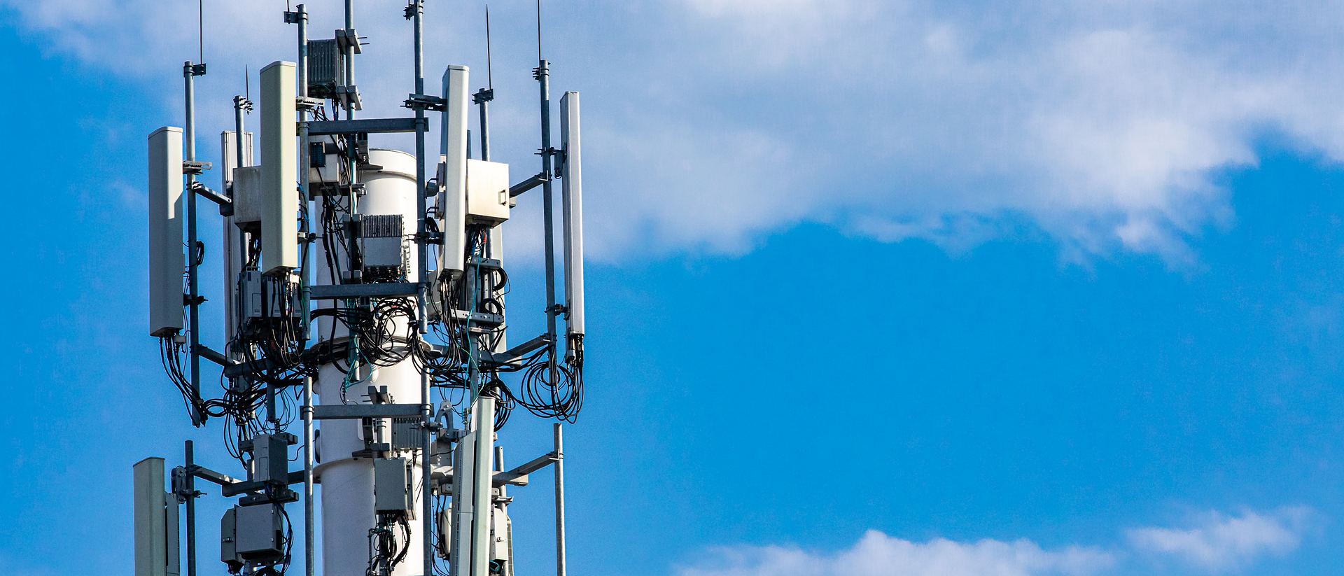 Telecommunication tower with antenna arrays against a bright sky